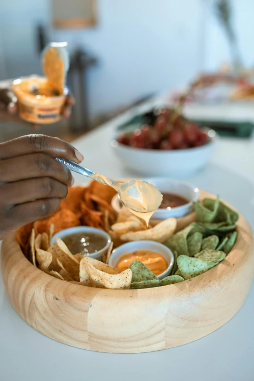 a person spooning food from a bowl of chips