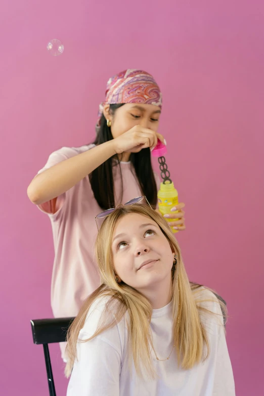 a girl sitting next to a woman who is brushing her hair