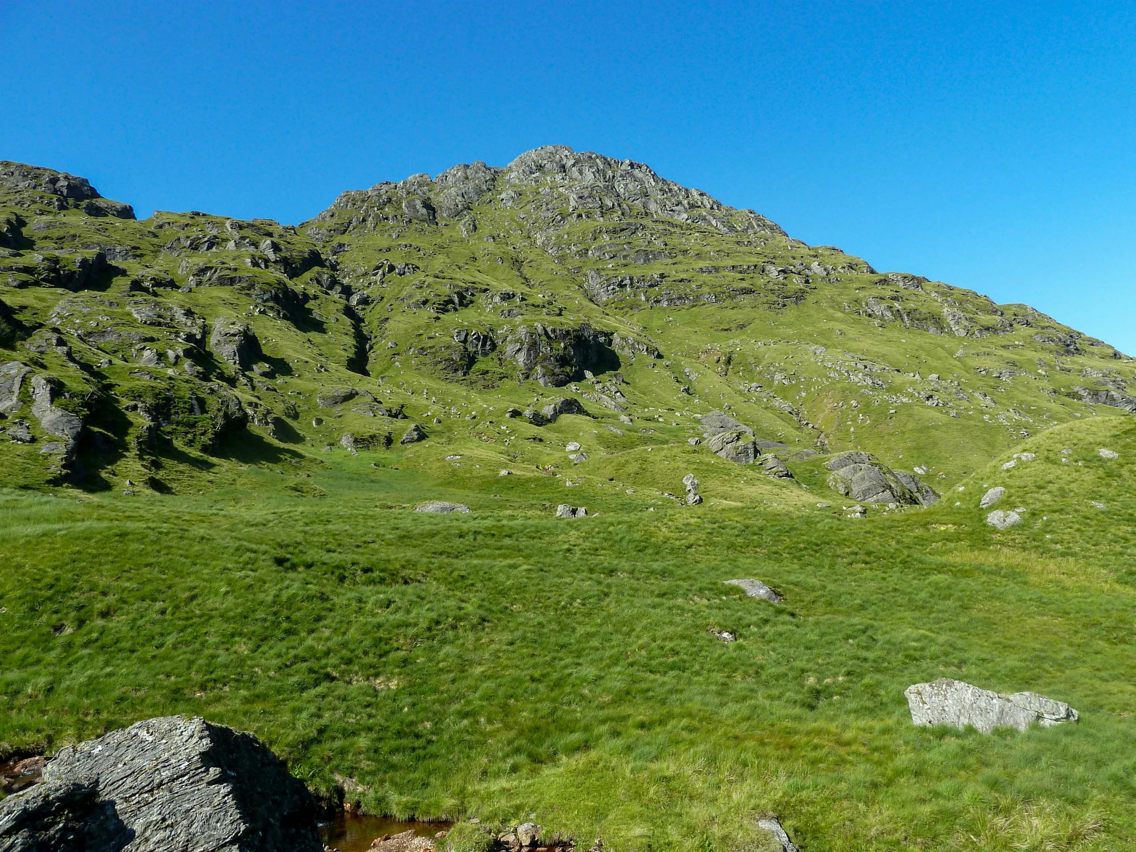 mountain side with a hillside and grass field