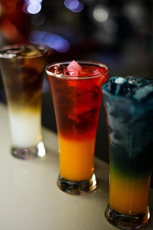 three colorful drinks are sitting on a table