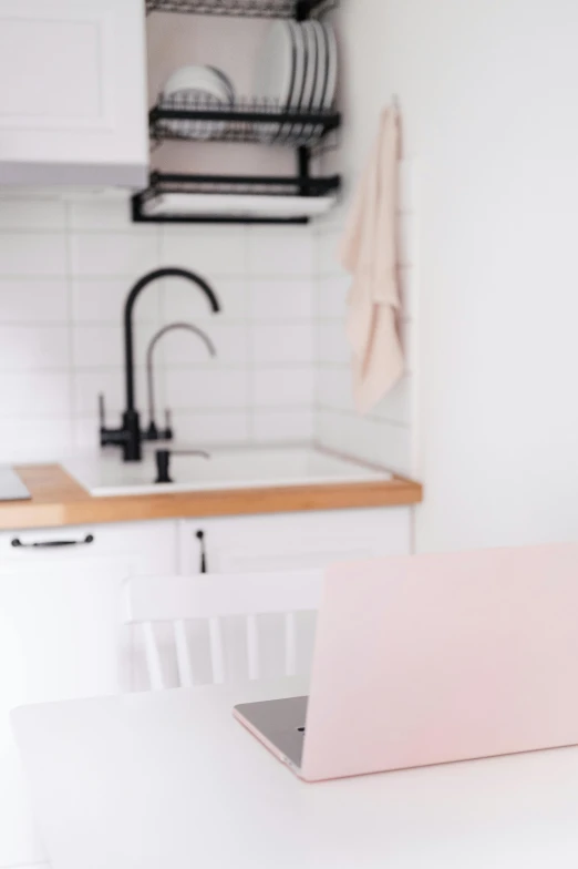 a laptop on a table next to a kitchen sink