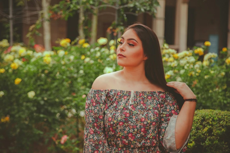 a woman standing in front of some pretty flowers