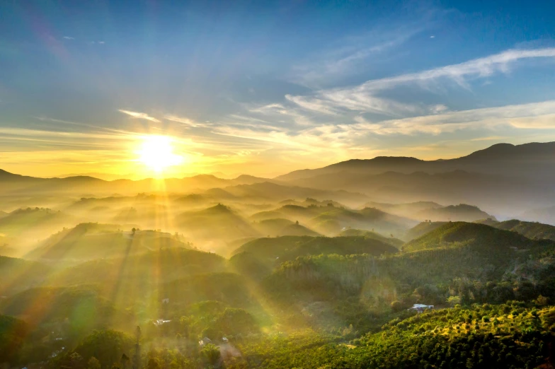 the sun sets over a mountain valley below