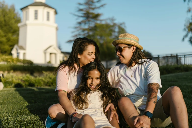 a man and two women sitting next to each other on the grass