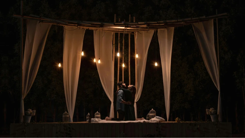 a couple standing under a canopy together in the night