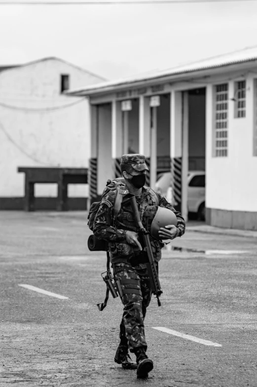 an army man walking across a parking lot with a backpack