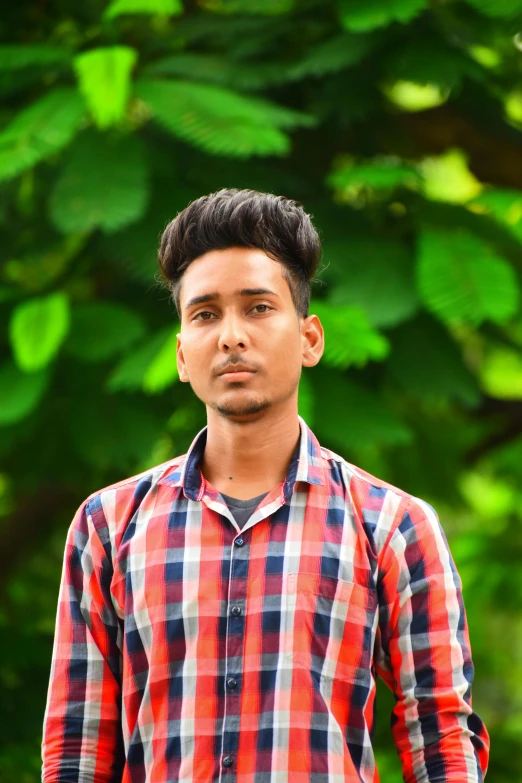 a young man in a plaid shirt poses for the camera