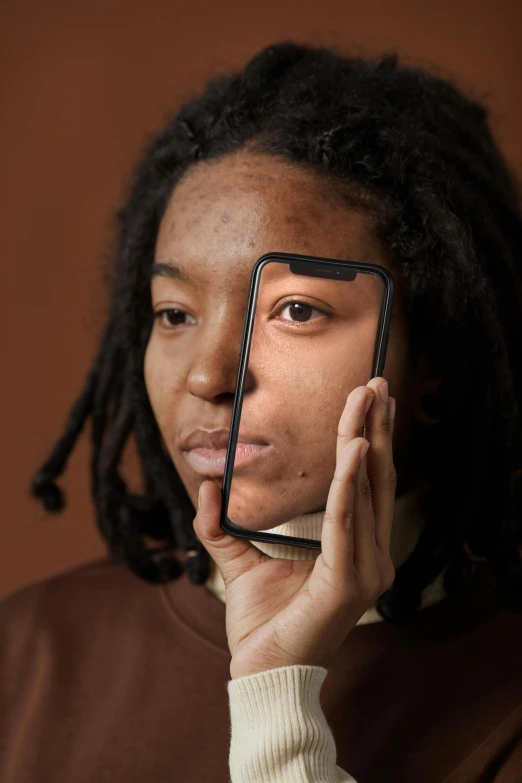 a person holding up a smart phone with dreadlocks