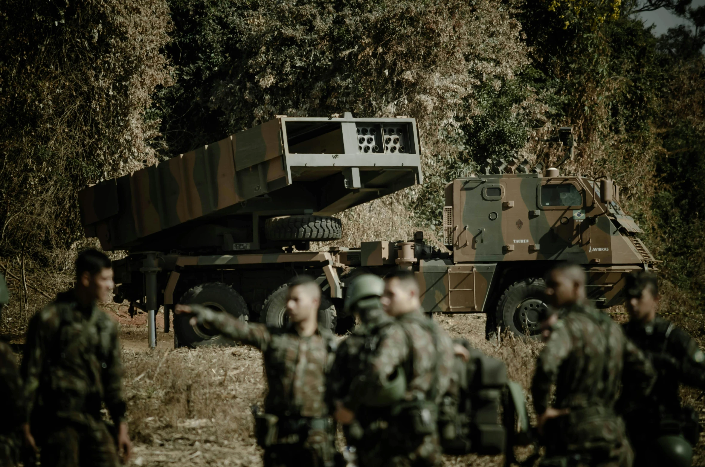 military personnel stand around a truck near trees