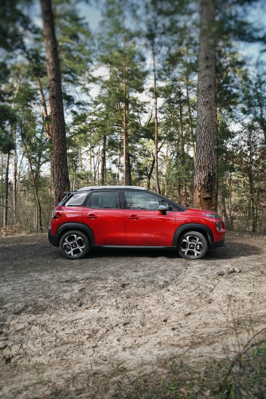 a small red car on a path through some trees