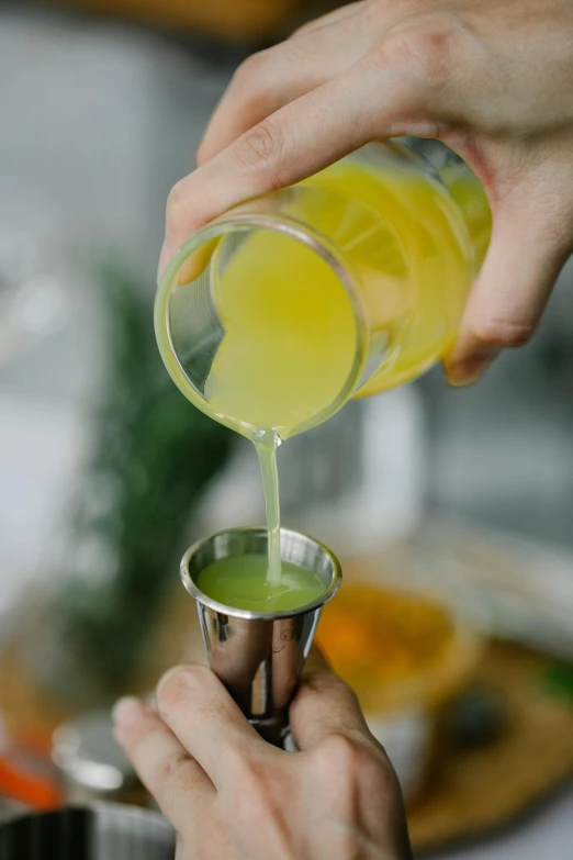 someone pouring green liquid in a small cup