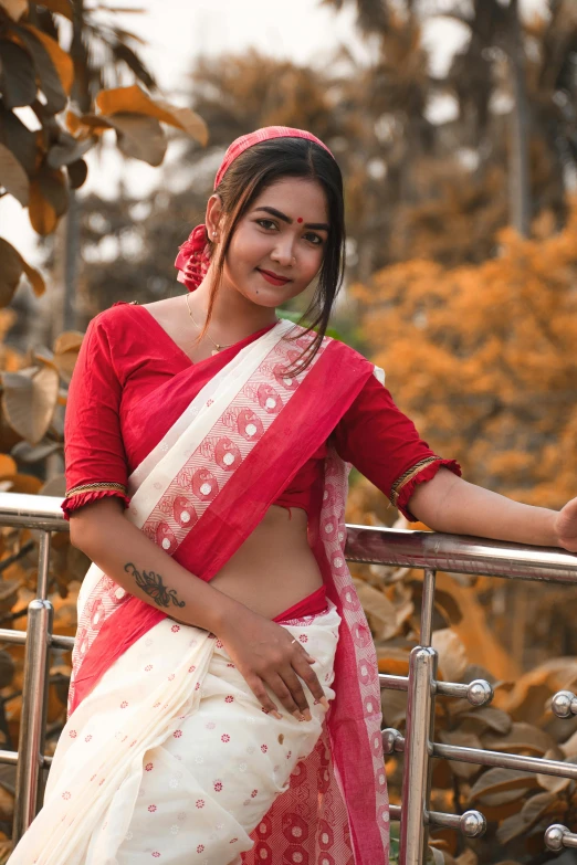 a woman with a red and white blouse on is leaning on a railing