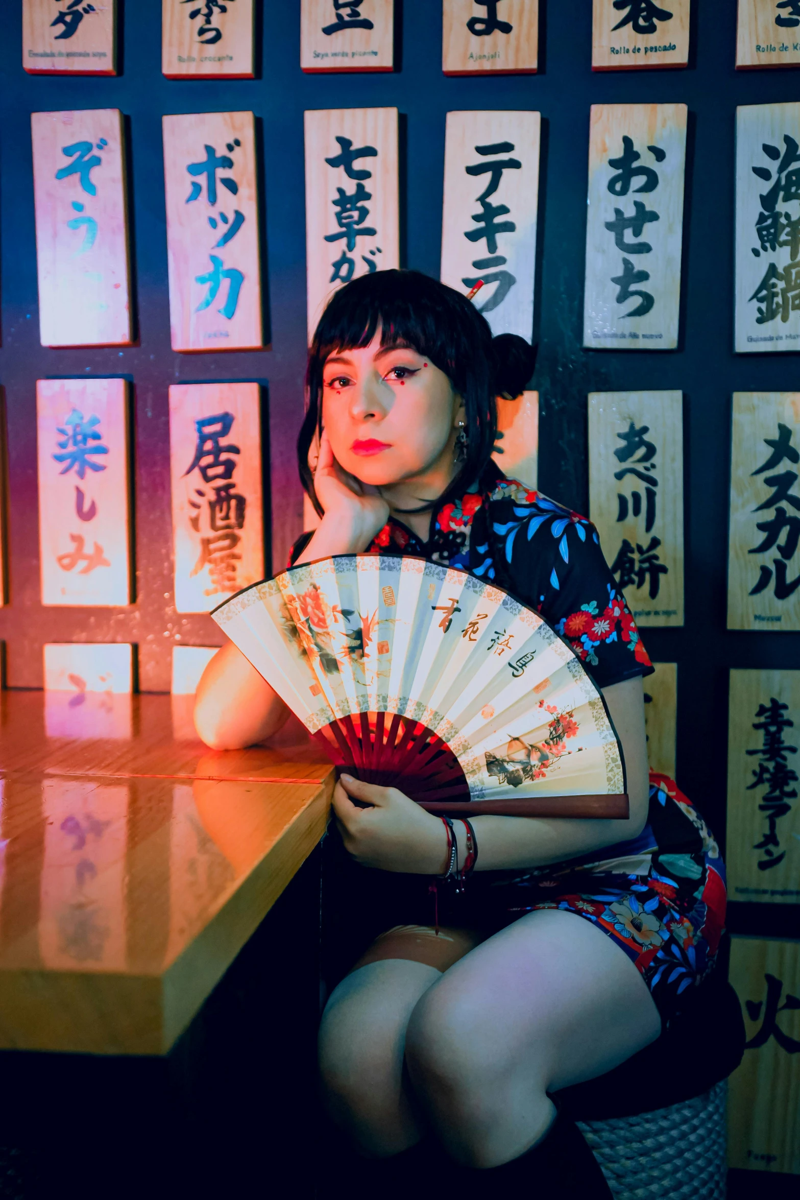 there is a young woman sitting at a table holding a fan