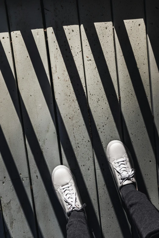 legs and feet on top of a sidewalk with shadows