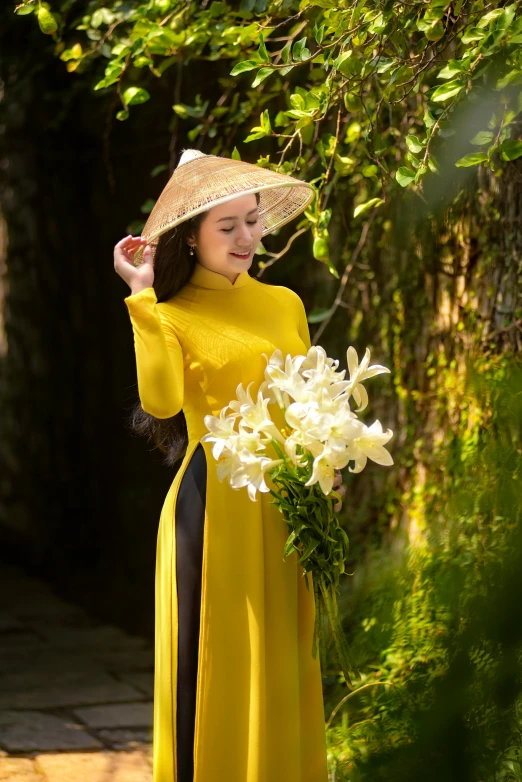 a woman in yellow is holding flowers and a straw hat