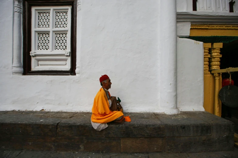 an indian man sitting on the step with his guitar
