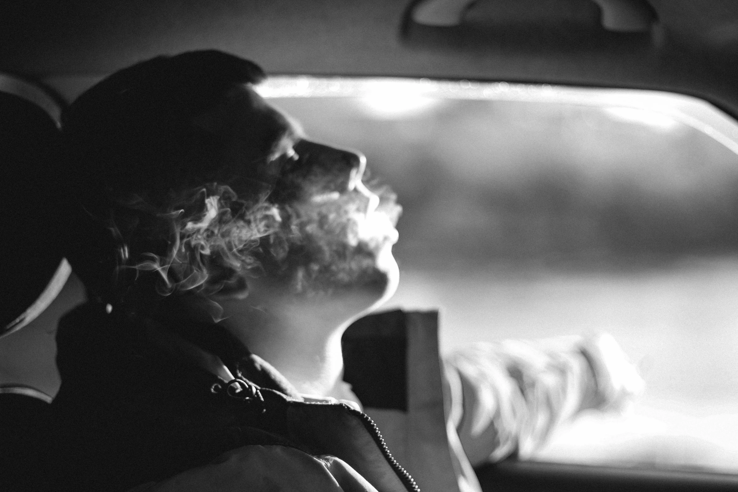 a man driving a car while smoking and holding a cigarette