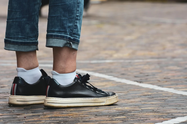 legs wearing black sneakers and socks on street