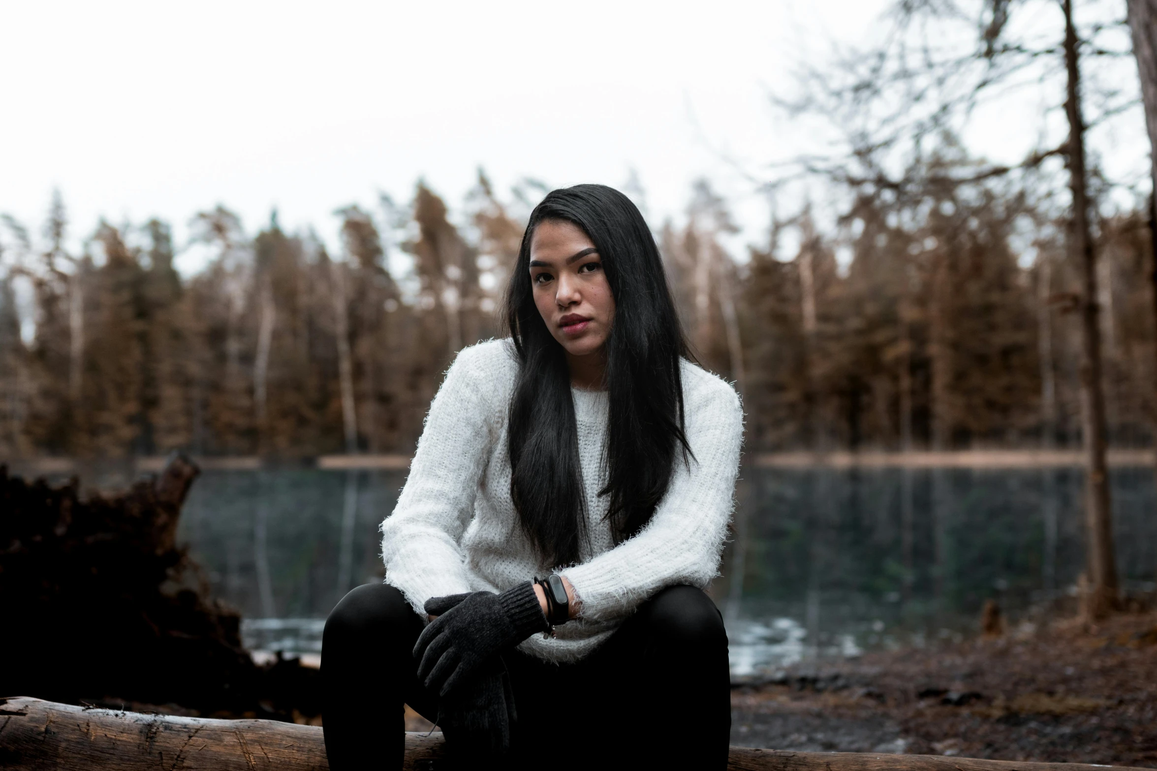 woman sitting on wooden post next to body of water