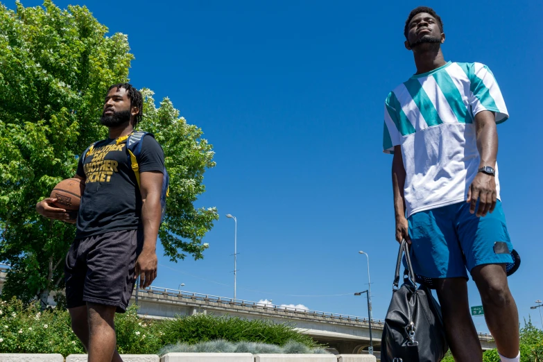 two young men standing with one of them looking up at the sky