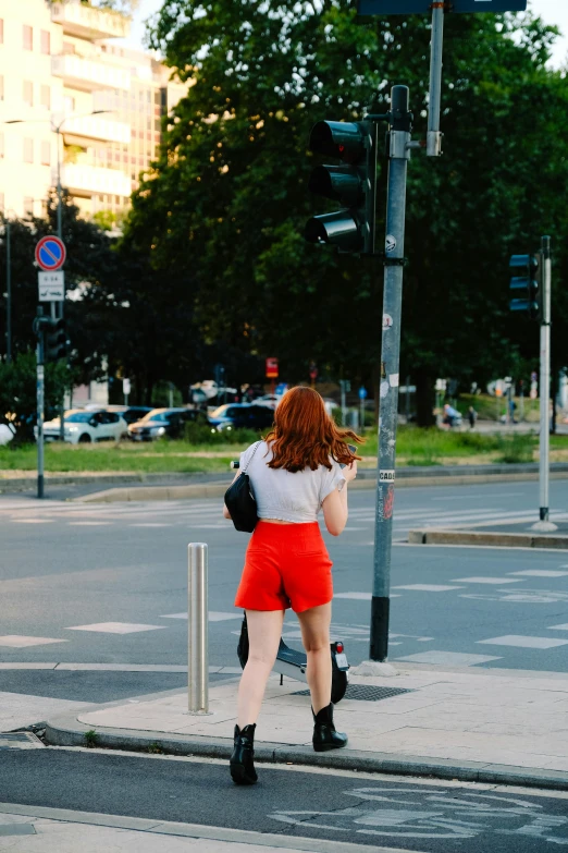 a woman in an orange skirt walks down the street