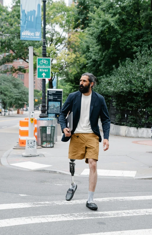 a man walking across a street wearing brown shorts