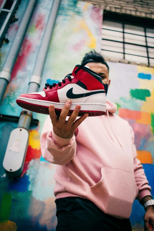 a woman is holding her red and black sneakers