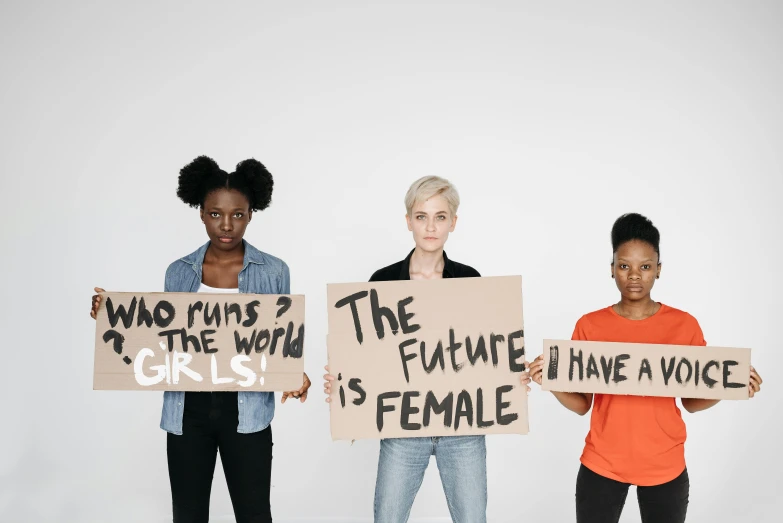 three women holding signs with words on them