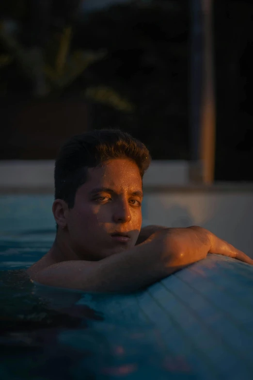 man looking back while laying on his side in the middle of a pool