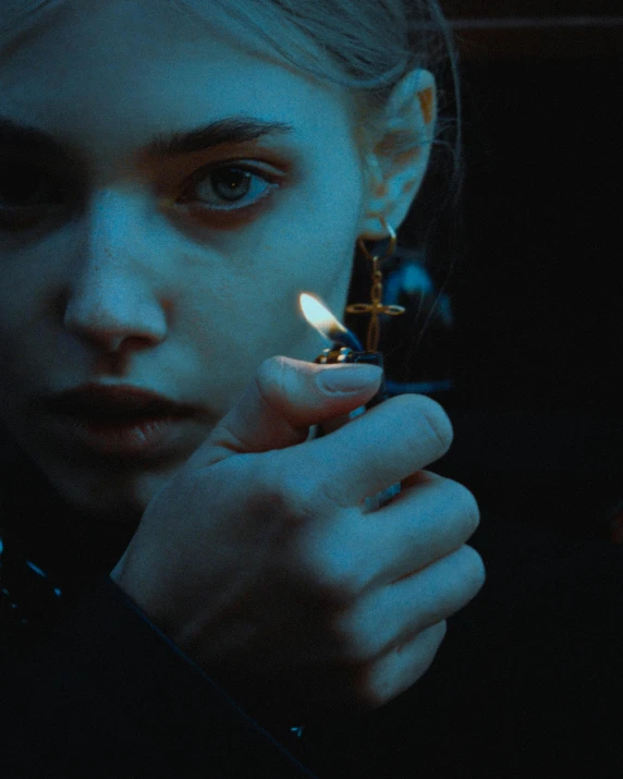 a young woman in the dark holding a cigarette lighter up