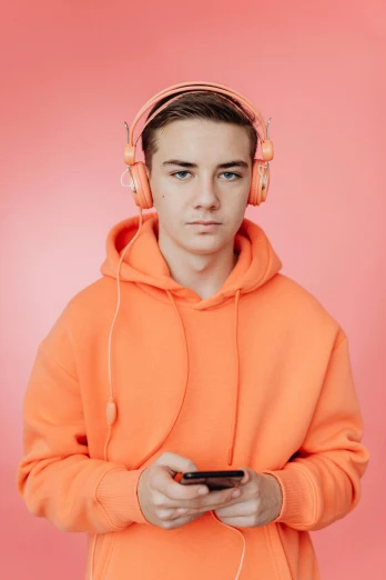 a boy in orange hooded jacket with headphones holding a remote
