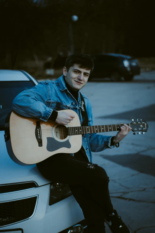 a person holding a guitar sitting on top of a car