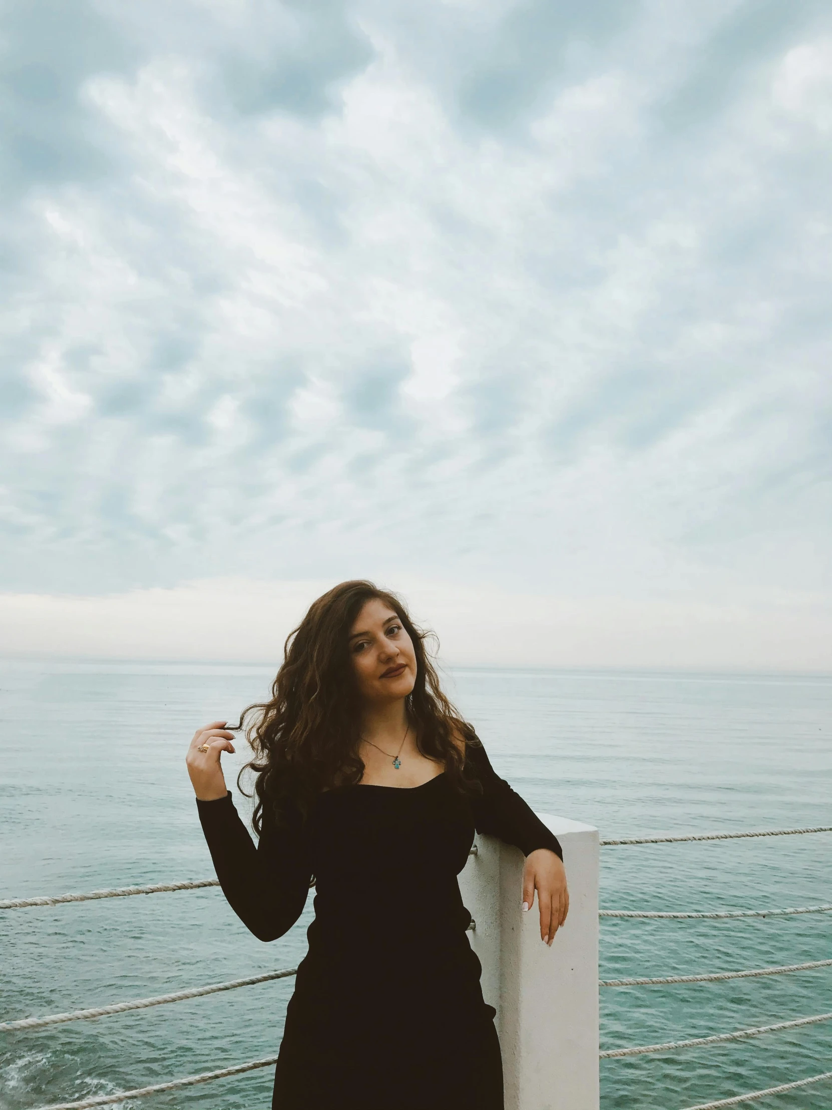 a girl with long hair stands near the water