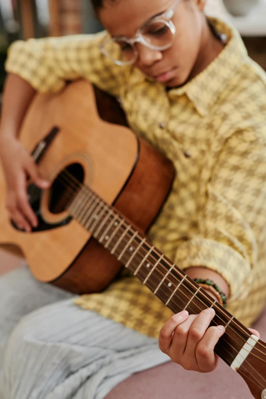 a  playing an acoustic guitar while sitting down