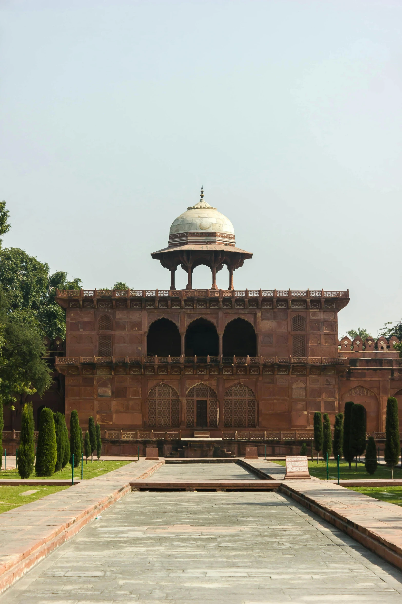 an empty square surrounded by greenery and a building with a domed roof