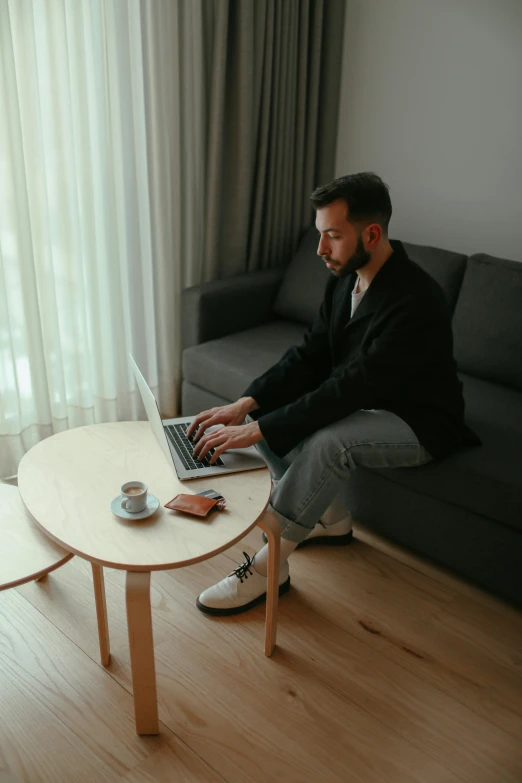 a man with a laptop on his lap is sitting on a coffee table