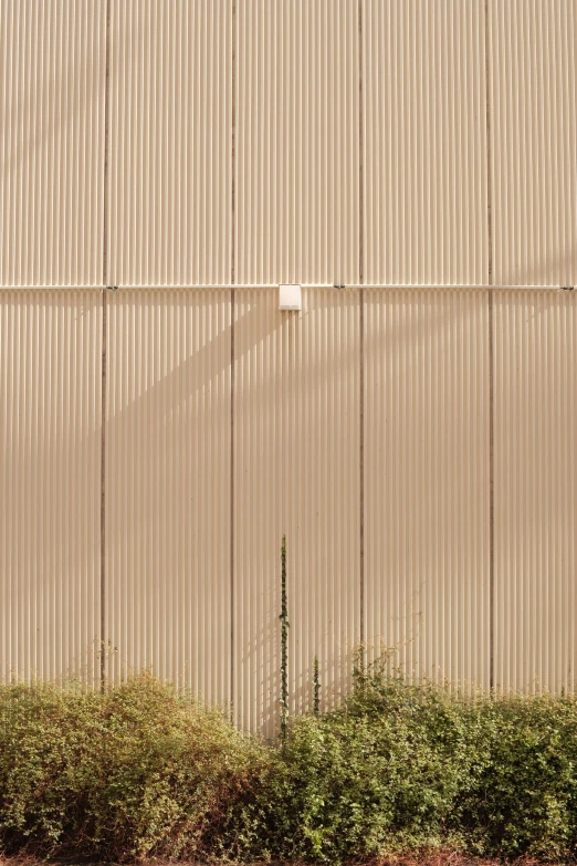 a parking meter in front of a large tan wall