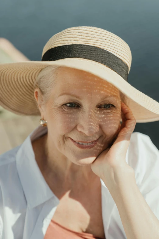 an old woman wearing a hat by the water