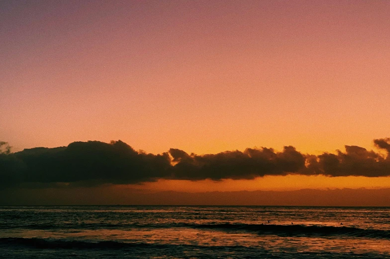 a colorful sky hangs over the ocean while a bird flies high above