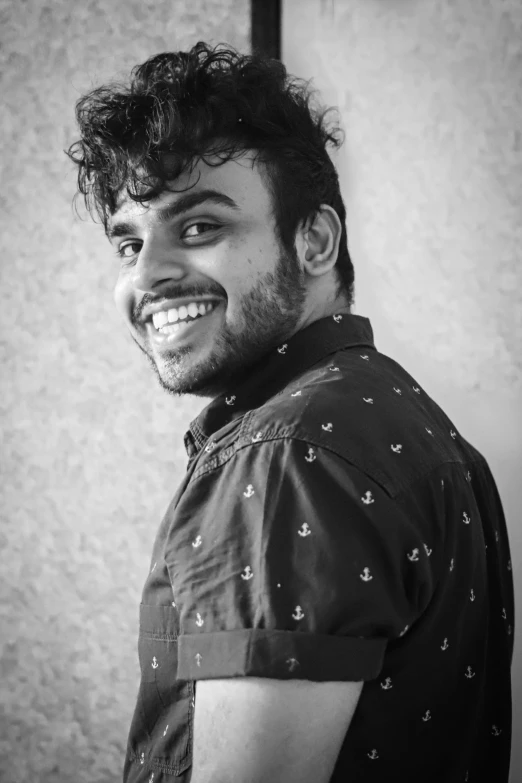 the young man has curly hair and is smiling