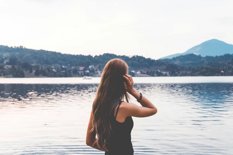 the woman is standing in front of the lake