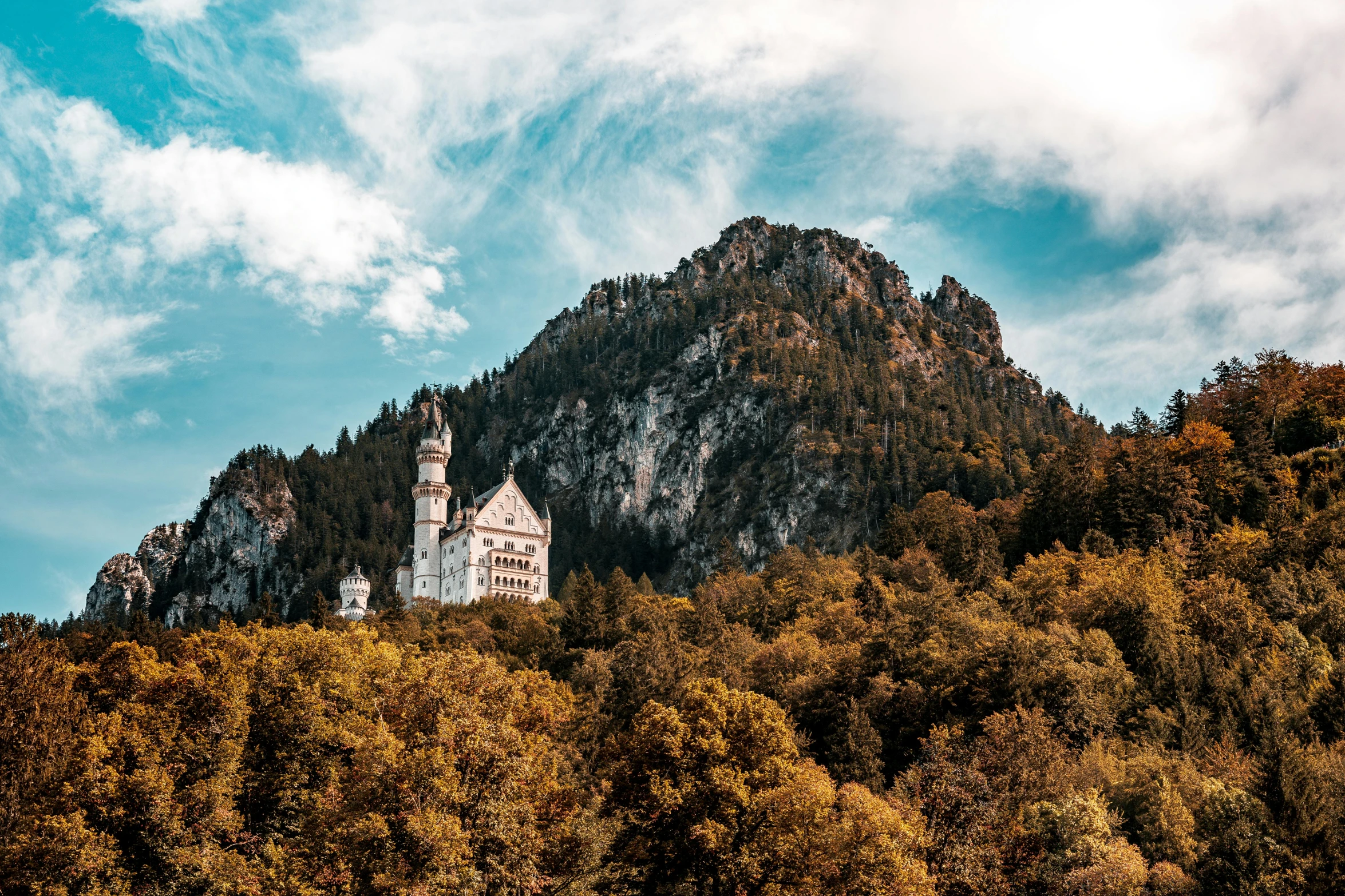 a tall white building with a tower is situated at the top of a mountain