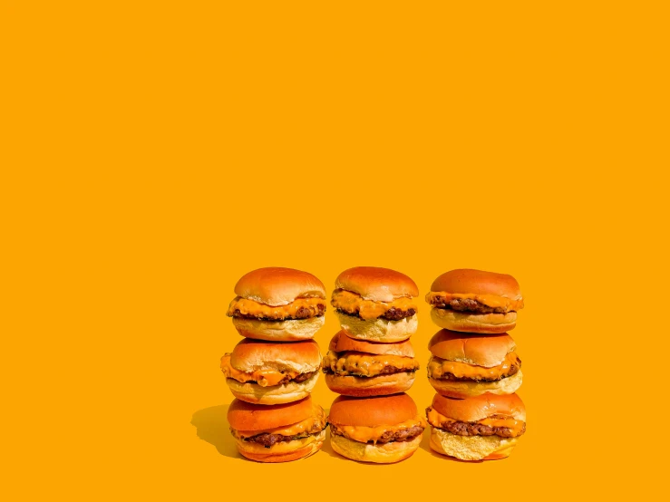 hamburgers sitting on top of each other in front of a yellow wall