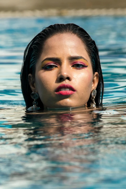 a girl is floating in the water with her hair pulled back