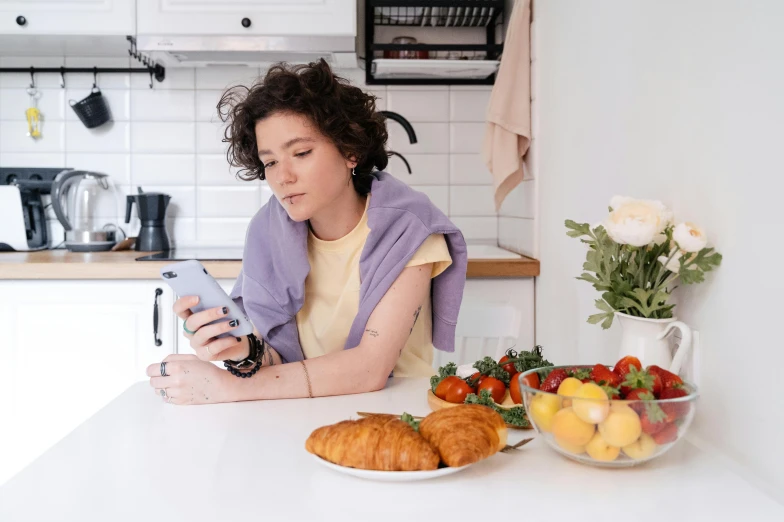 a woman sitting at a kitchen counter with food