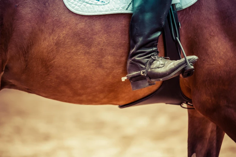 a woman in boots riding on the back of a brown horse