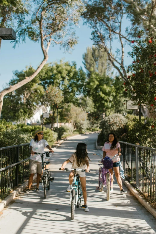 three people standing on the street one riding a bike