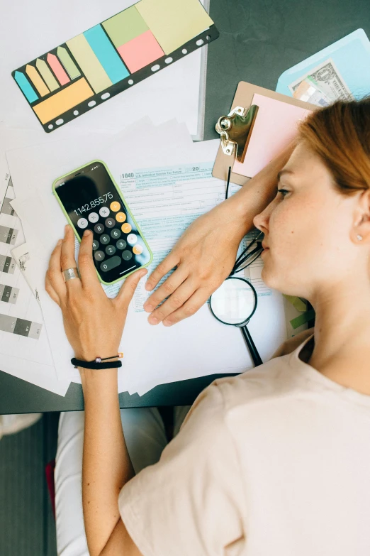 a woman is making notes on paper and a calculator