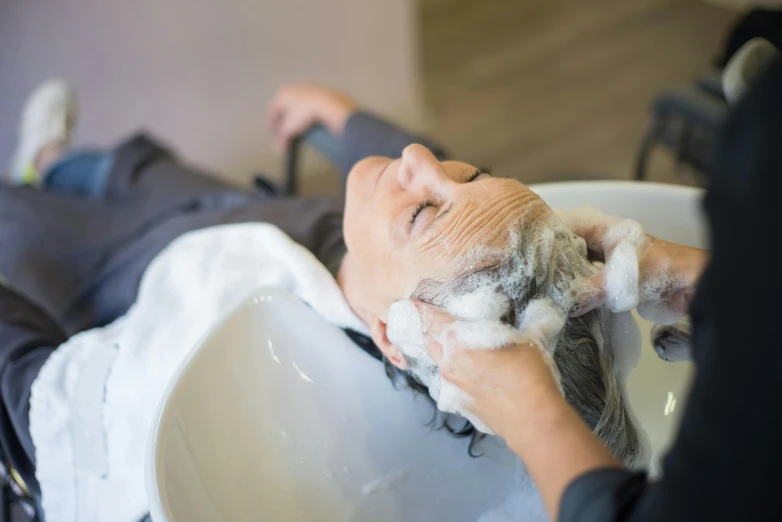 the woman is getting her hair washed at the salon