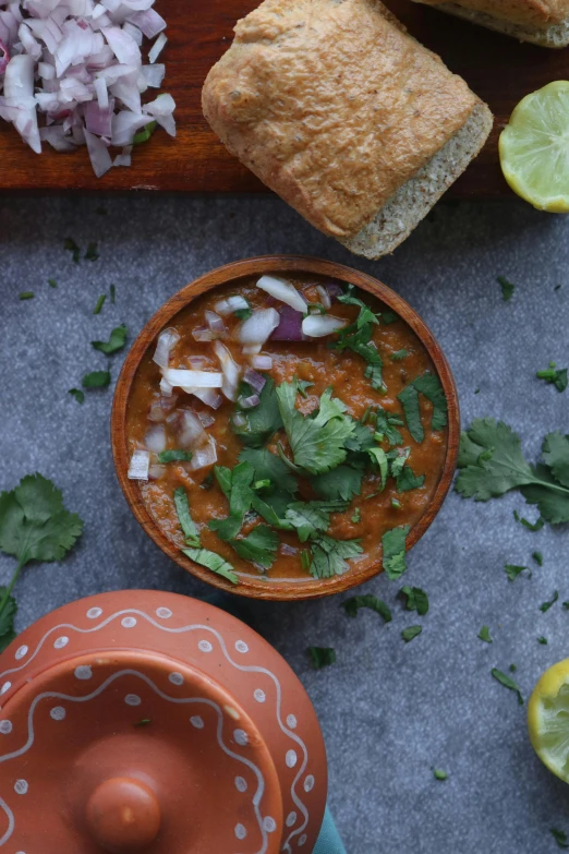 a bowl of chili on a counter next to a  board and limes